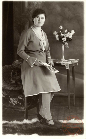 [Portrait d'une femme assise sur le bord d'un fauteuil et tenant un magasine]