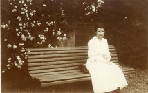 Photographie de Yvonne Hourte en robe blanche assise sur un banc en 1923]